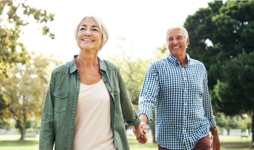 man and woman walking in park while holding hands