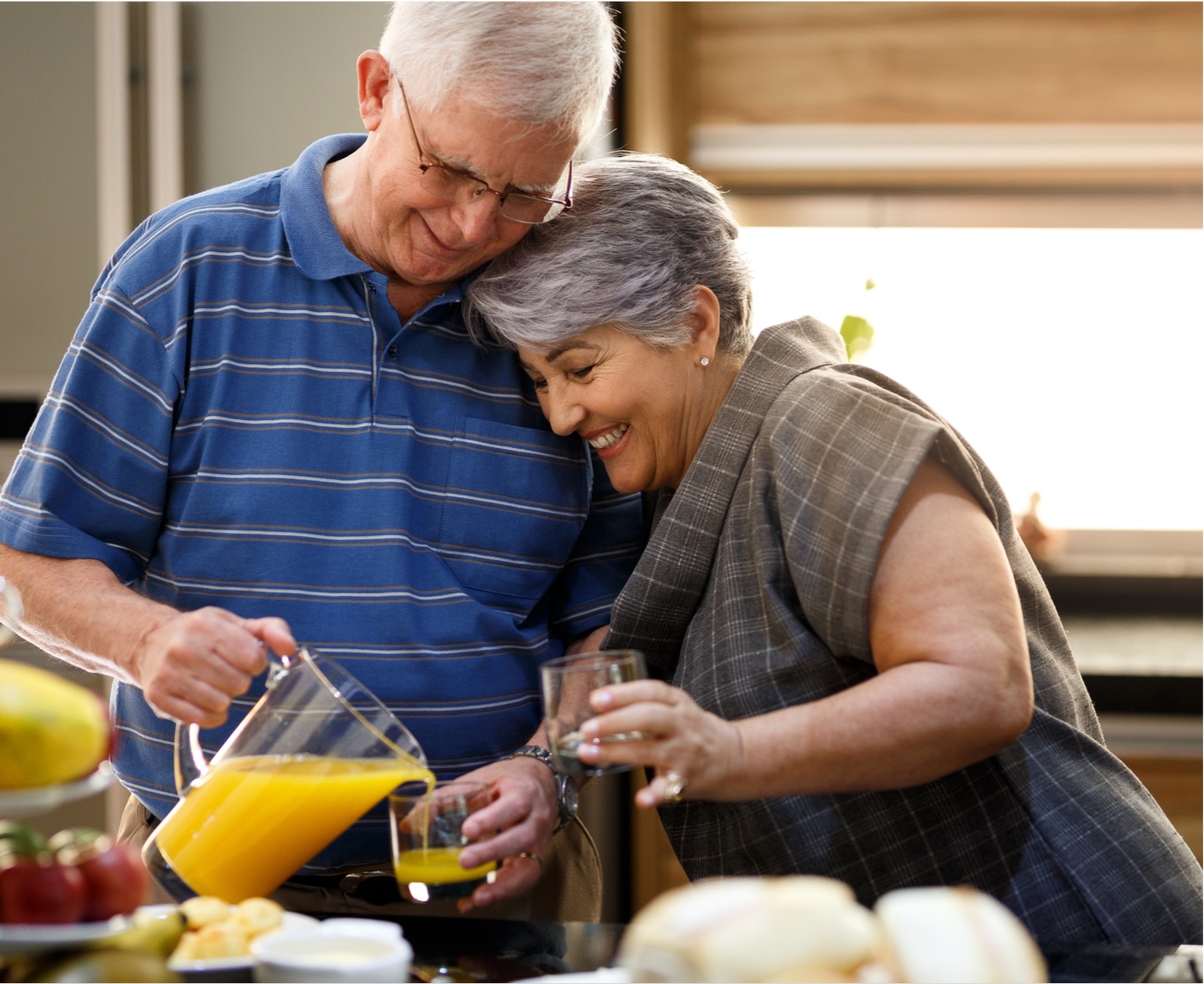 older adult man and woman pouring juice in kitchen