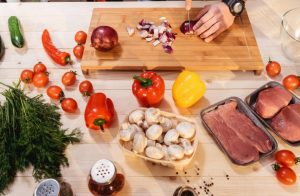 cooking for two hands chopping fresh vegetables, meat and spices on cutting board